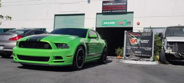Bright green sports car parked outside a building with signs and trash bins nearby