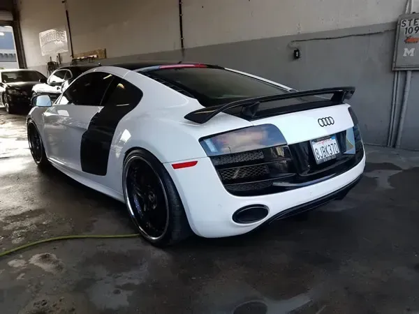 White Audi sports car with black accents parked in a garage.