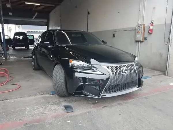 Black Lexus SUV parked in a garage bay, front wheel turned outward.