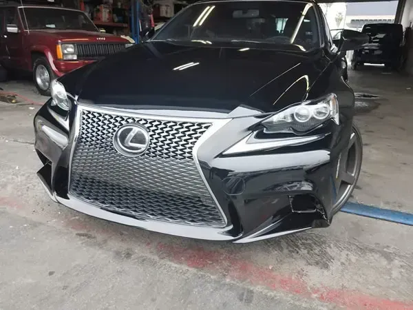 Black Lexus sedan parked in a garage, front view with silver grille and headlights