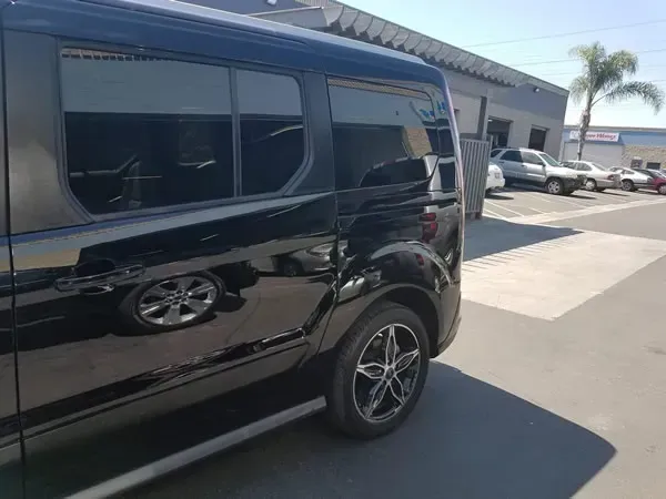 Black van parked outside a building in a sunny lot