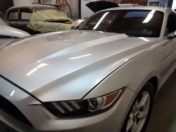Silver sports car parked in a garage with other vehicles nearby