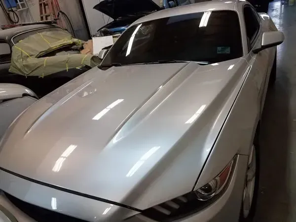 White sedan parked in a garage, front view with headlights visible