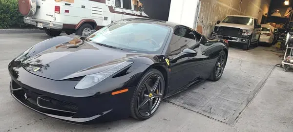 Black sports car parked in a driveway outside a garage, front-left view