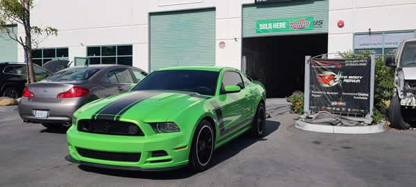 Bright green sports car parked outside a storefront beside a shopping cart corral