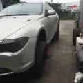 White car parked tightly beside a darker vehicle in a narrow lot.