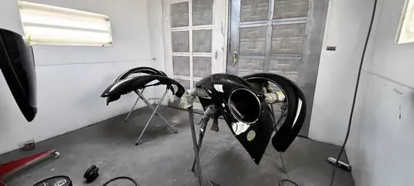 Black automotive body panels and frames in a workshop with a window and concrete floor