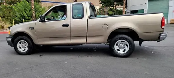 Beige pickup truck parked on a street, side view.