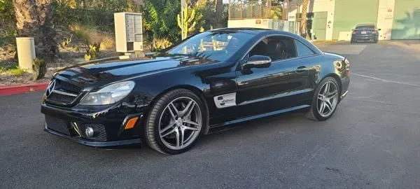Black sports coupe parked on a street, viewed from the front side in daylight.
