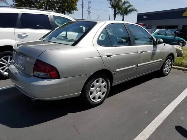 Silver sedan parked in a sunlit parking lot рядом with other cars and palm trees