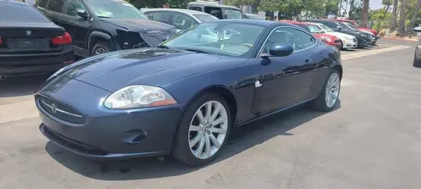 Blue sports car parked in a lot beside other cars on a sunny day