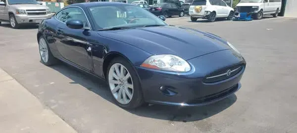 Dark blue coupe parked outdoors in a lot, angled front view