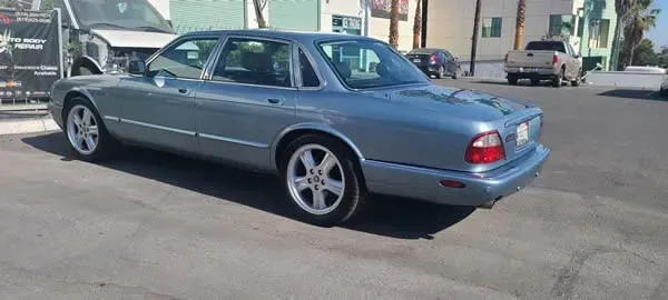 Blue two-door sports coupe parked on a sunny street near buildings and other cars.