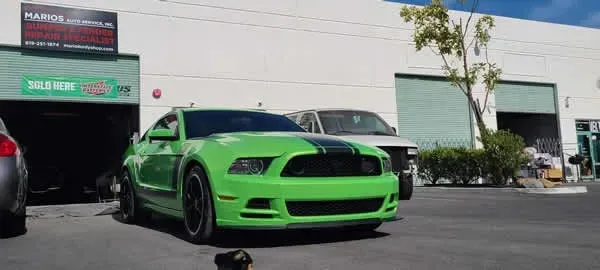 Bright green sports car parked outside a garage on a sunny day