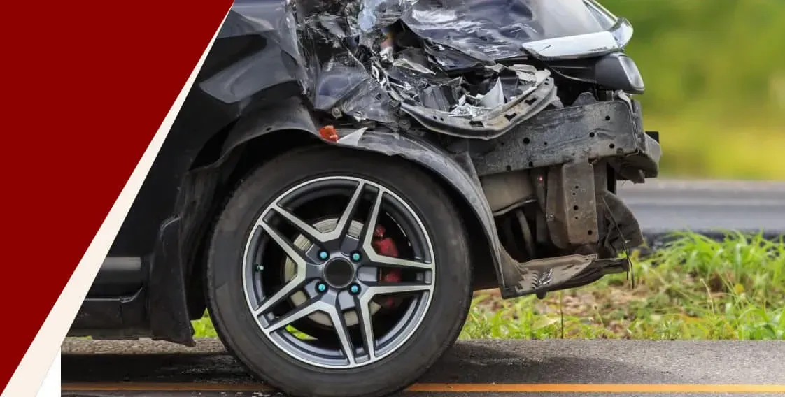 Damaged black car front end after collision beside a roadside guardrail