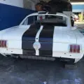 White vintage car with twin blue racing stripes parked in a garage, front view