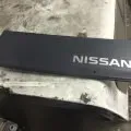 Close-up of a black Nissan logo on a dark panel with a white surface below