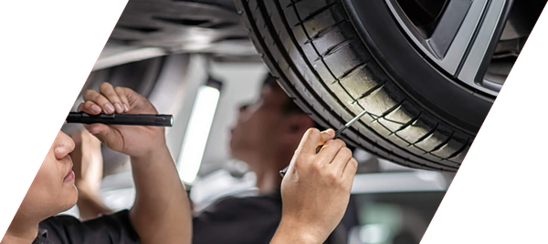 Mechanic inspecting a car tire with a tool in an auto repair shop
