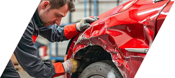 Mechanic repairing a dented red car fender in an auto body shop