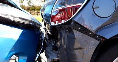 Two cars with severe rear-end collision damage, blue car crushed into dark gray car