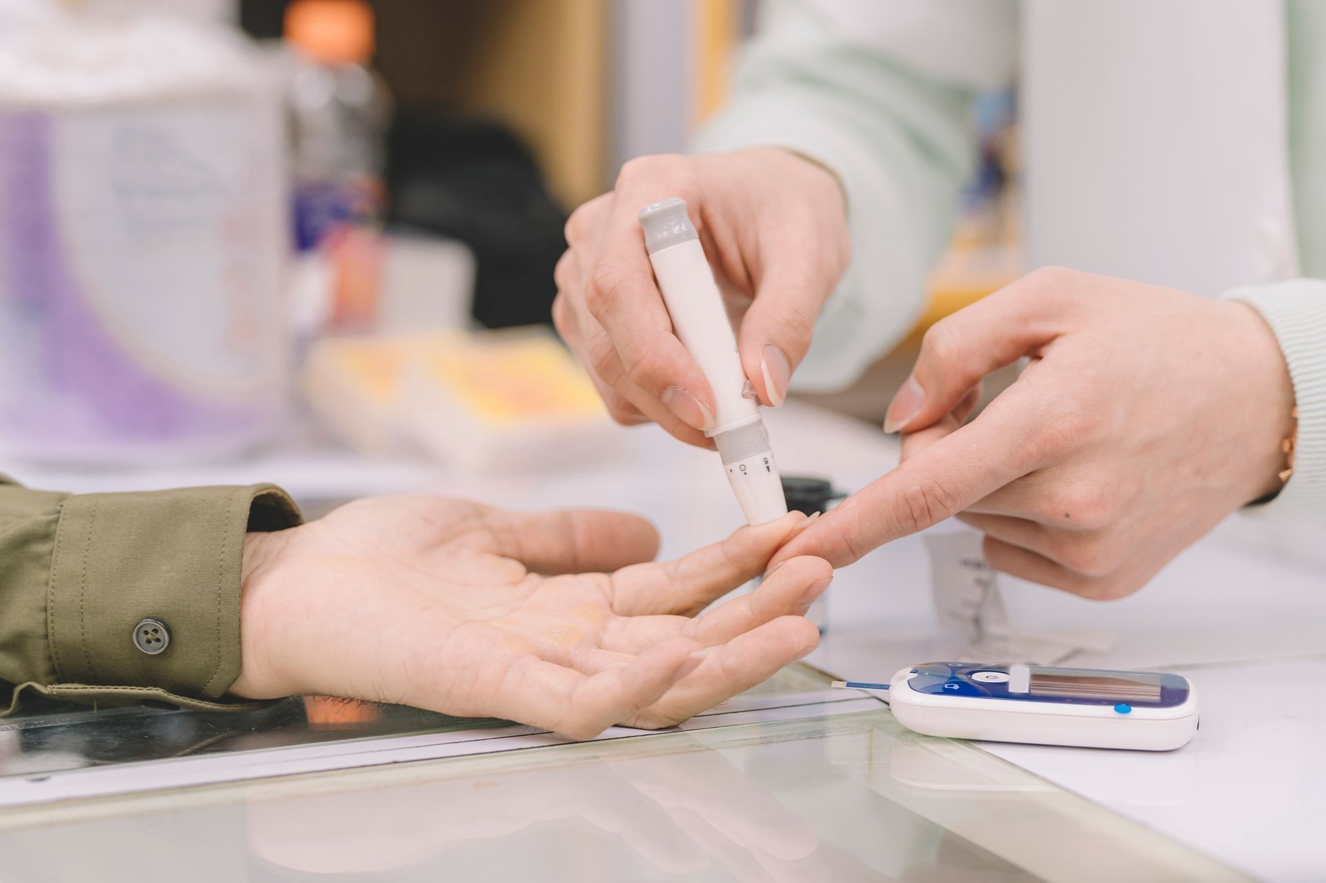 Un operatore sanitario punge il dito di una persona per un test della glicemia su un lettino di una clinica.