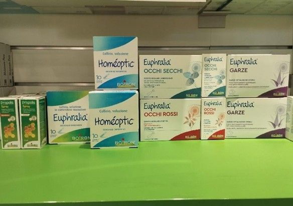 In un negozio, uno scaffale con scatole di prodotti Euphidra e omeopatici è appoggiato su un bancone verde brillante.