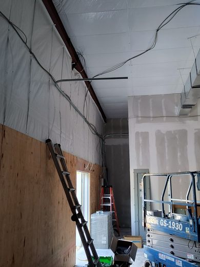 Construction site interior with exposed wiring and a ladder, and a blue lift.