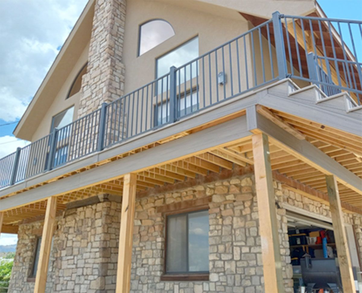 A house with a stone exterior and a deck with metal railings.