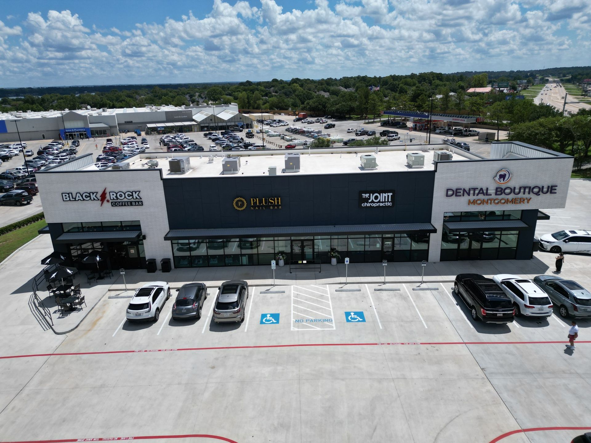 A commercial building with several businesses, including a dental office. Cars parked out front under a partly cloudy sky.