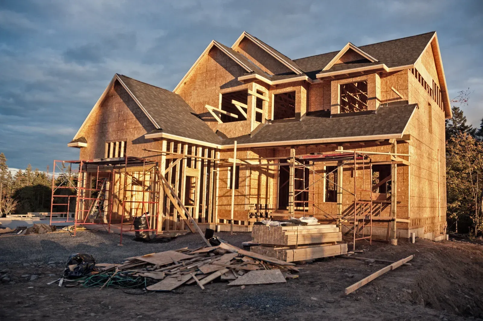 A two-story house under construction; wooden frame visible against a blue sky.