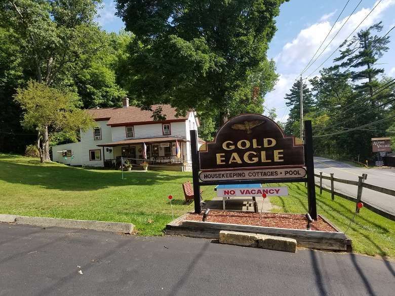 Gold Eagle motel sign in front of a white building and green trees on a sunny day