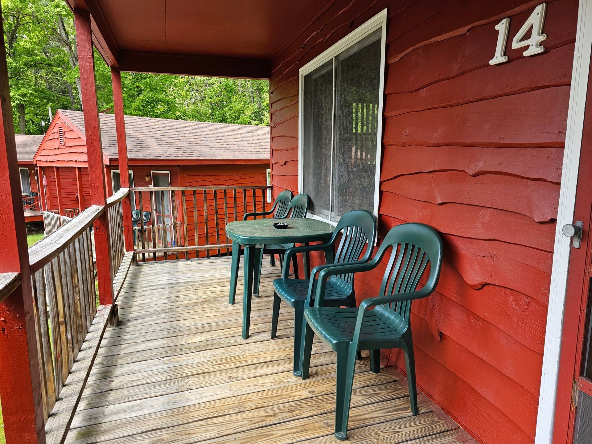 Red porch with green chairs and table, white door, and house number 14