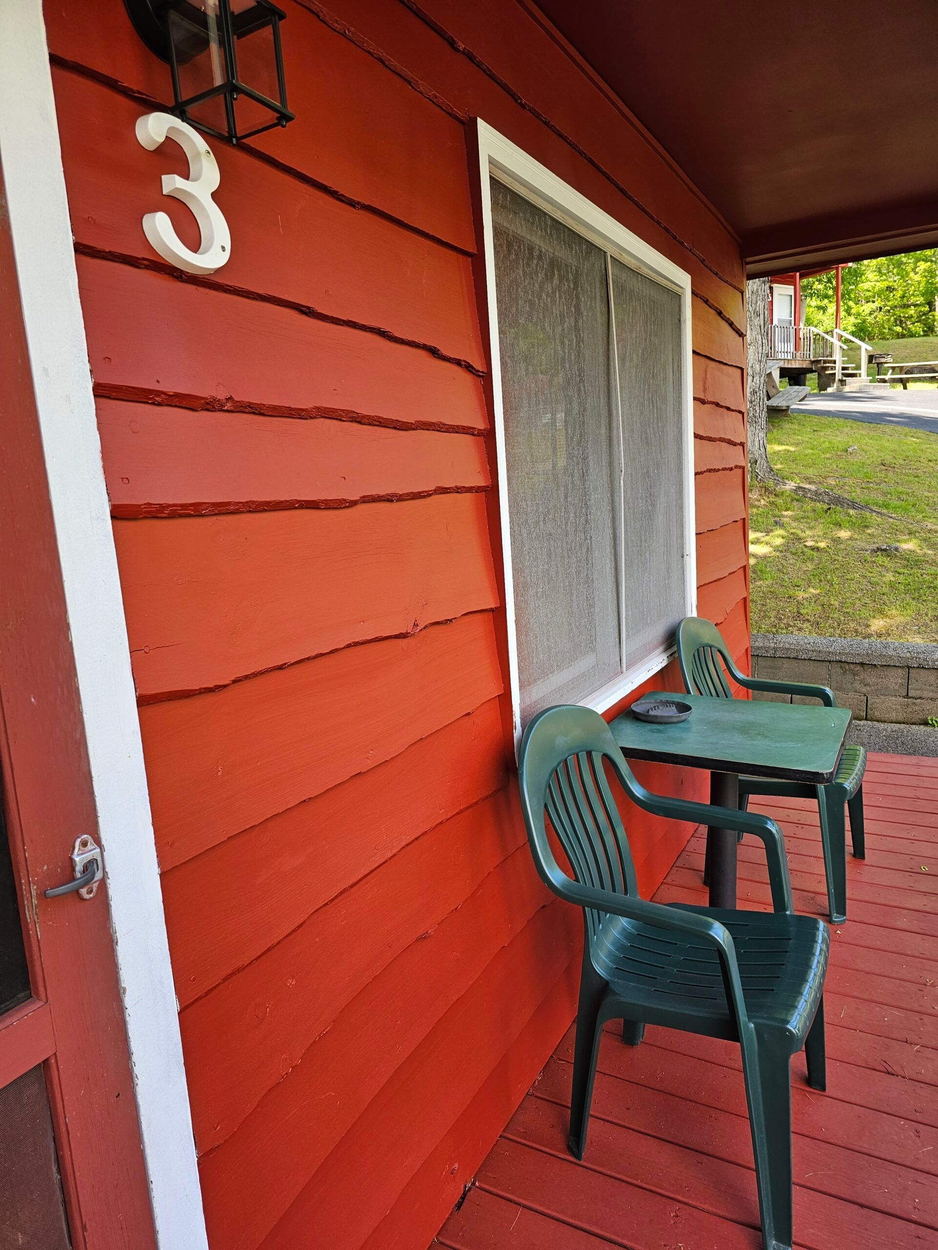 Orange apartment entry with white-trimmed window, green chairs, and unit number 3 on the wall