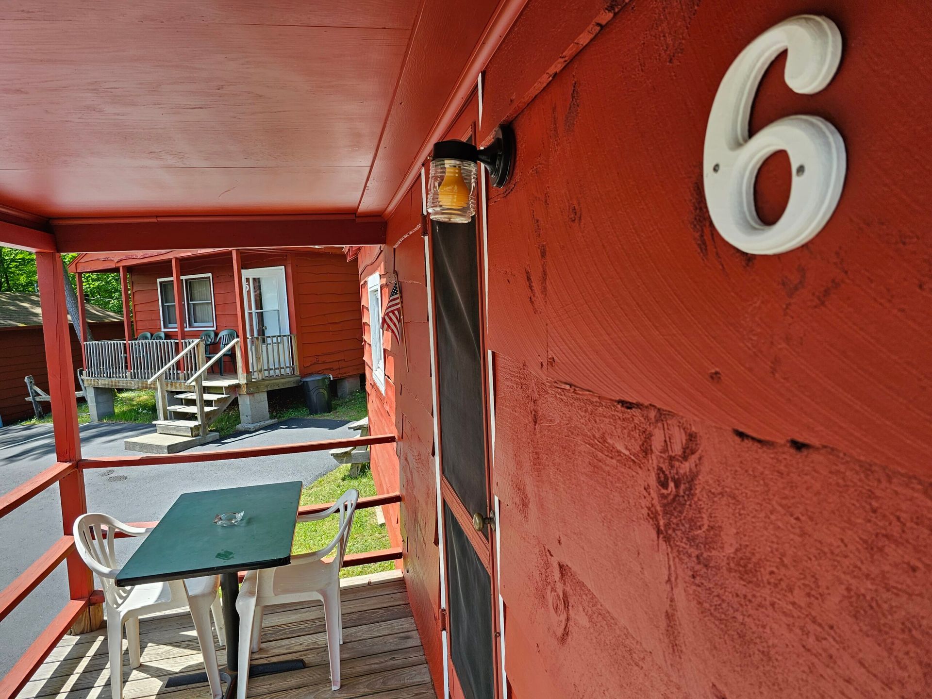 Red motel walkway with table, chairs, and room number 6 on the wall