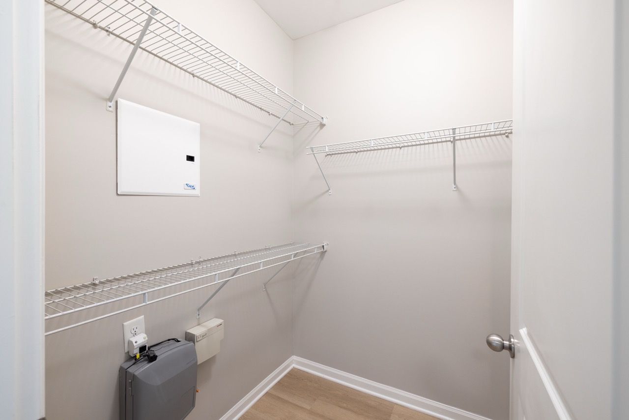 Walk-in closet with white wire shelving and a small utility area near the door.