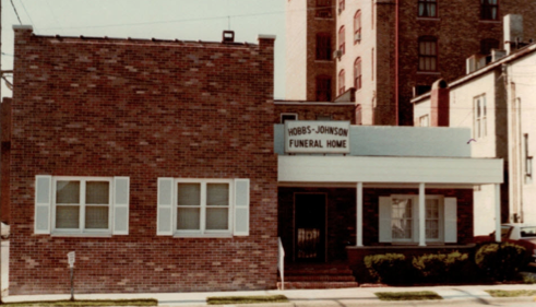 Honds-Johnson Funeral Home with a brick exterior, white-shuttered windows, and a covered front porch entrance.