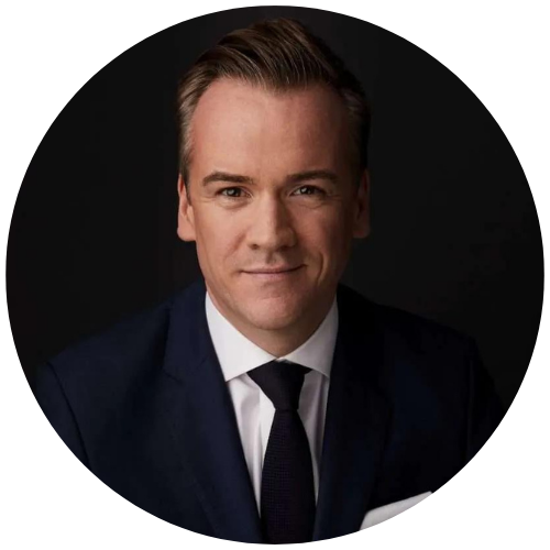 Studio portrait of a man in a dark suit and tie against a black background
