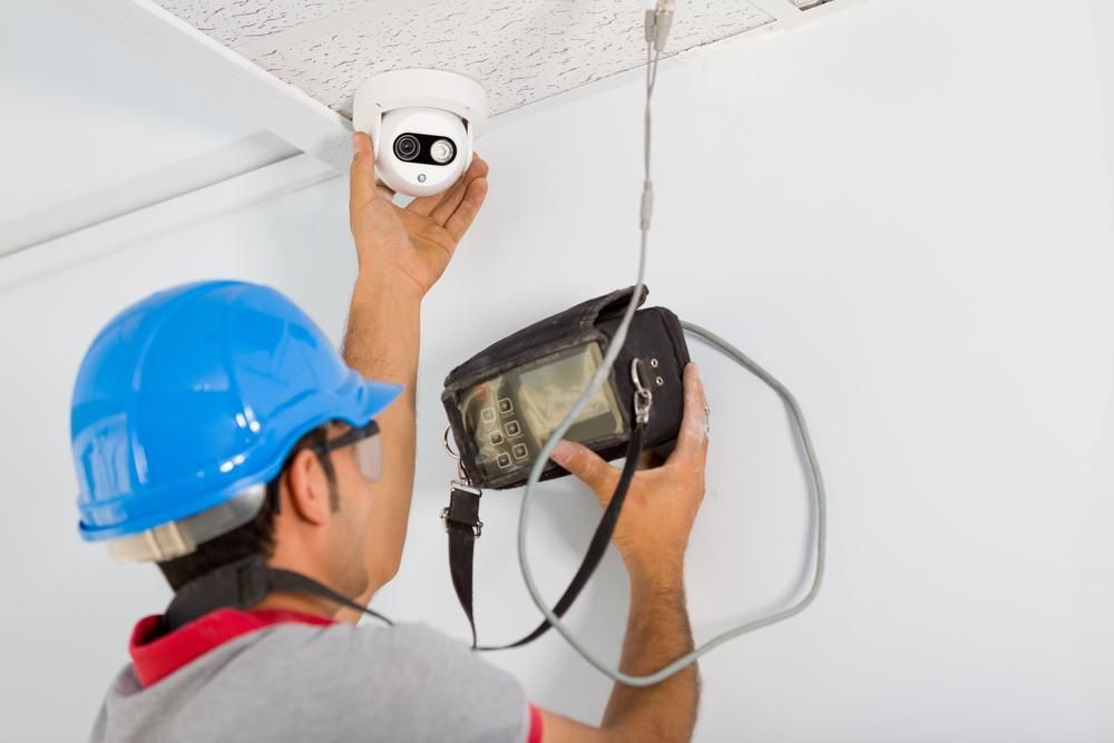 A Man Is Installing a Security Camera on The Ceiling — MNC Security in Emerald Beach, NSW
