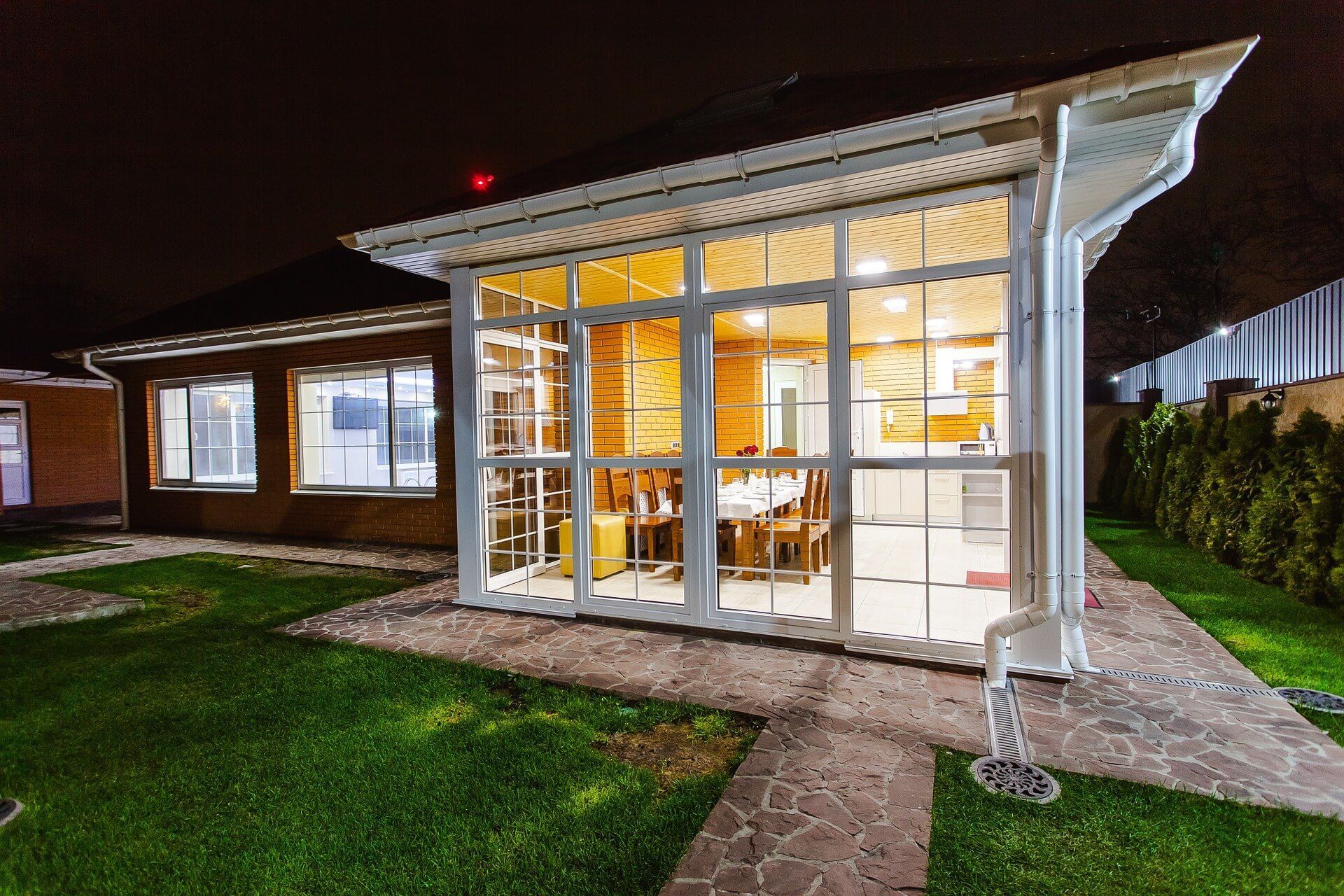 A house with a lot of windows and a patio at night.