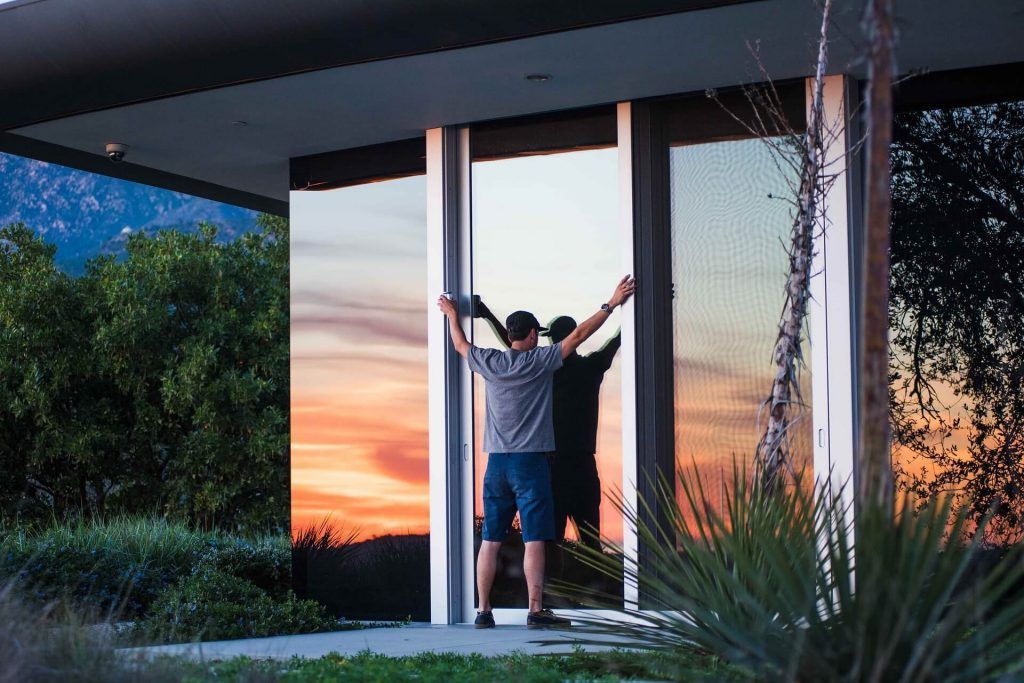 A man is standing in front of a house with his arms outstretched.