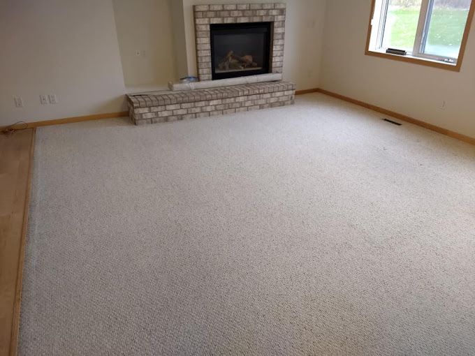 A living room with a fireplace and a large white carpet.