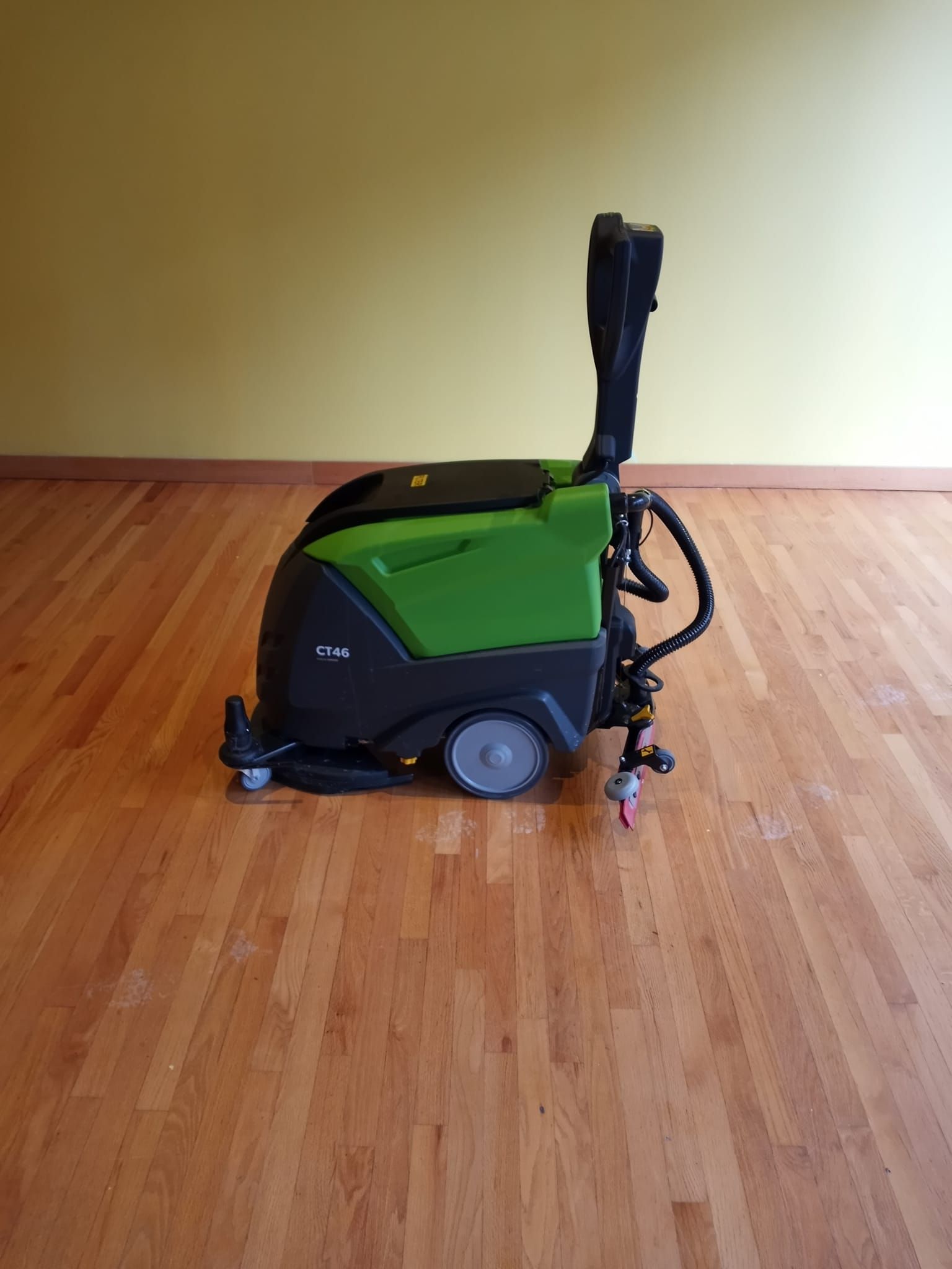 A green and black machine is sitting on a wooden floor