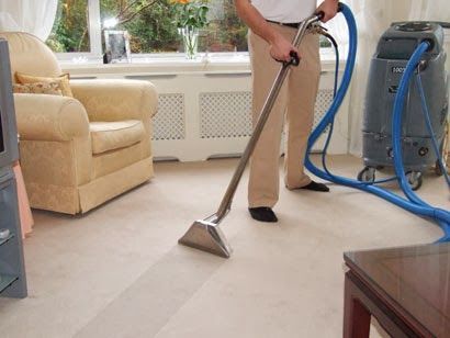 A man is using a vacuum cleaner to clean a carpet in a living room.