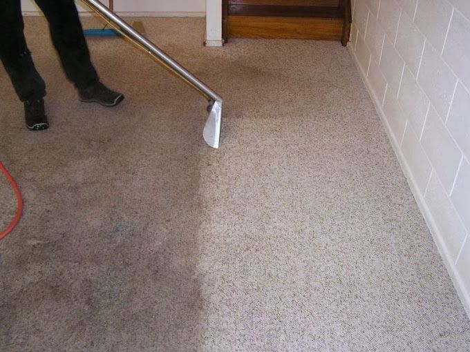 A person is cleaning a carpet with a vacuum cleaner.