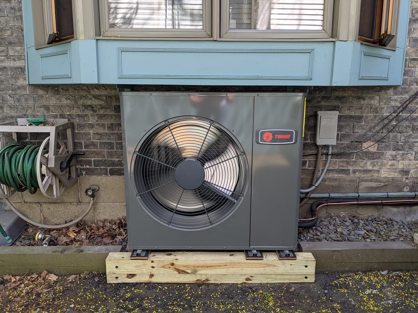 A large fan is mounted on the side of a building next to a window.