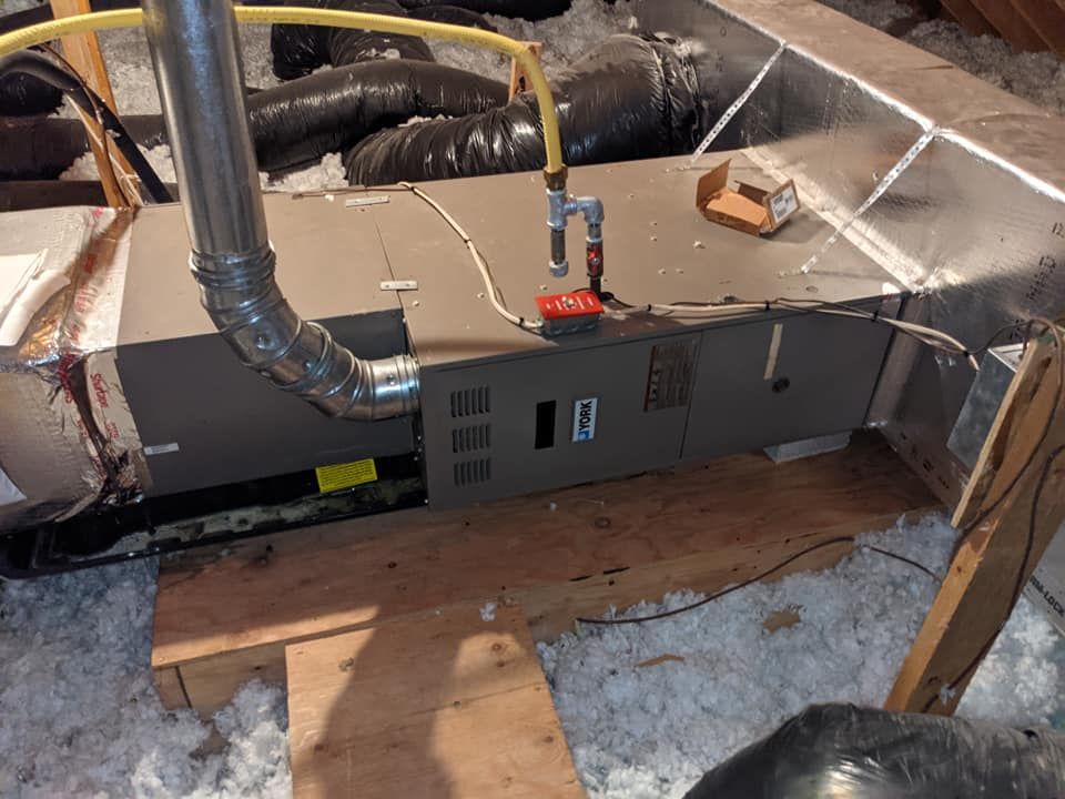 An air conditioner is sitting in the attic of a house.