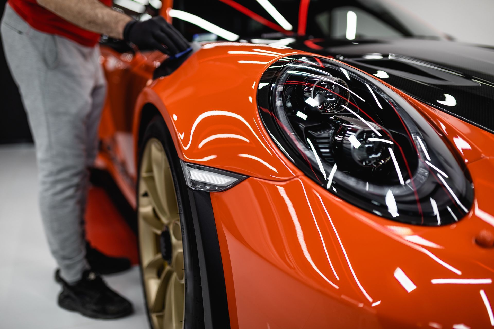 Close-up of an orange sports car with a person opening the door in a garage Close-up of an orange sports car with a person opening the door in a garage