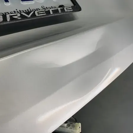Close-up of a white car bumper with a dealership plate visible at the top