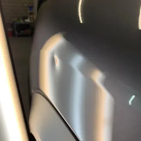 Close-up of a black office chair with bright light reflections on the backrest