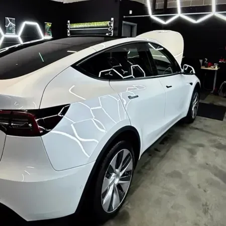 White SUV in a dark showroom with geometric LED wall lights and its rear hatch open